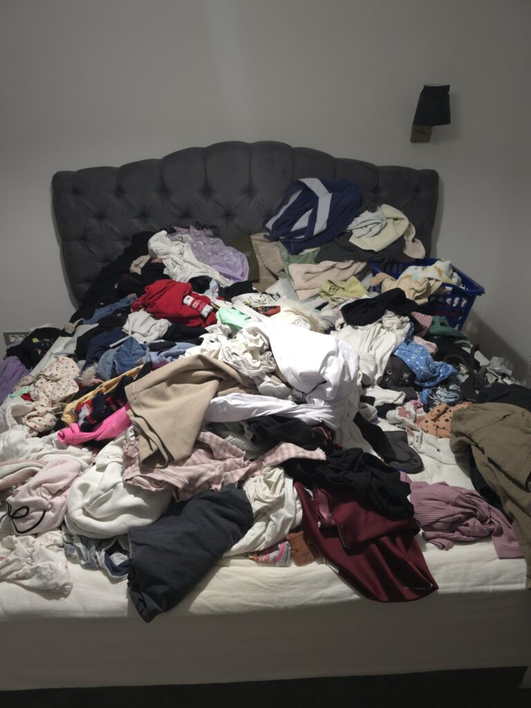 Clean laundry piled on the bed before organizing
